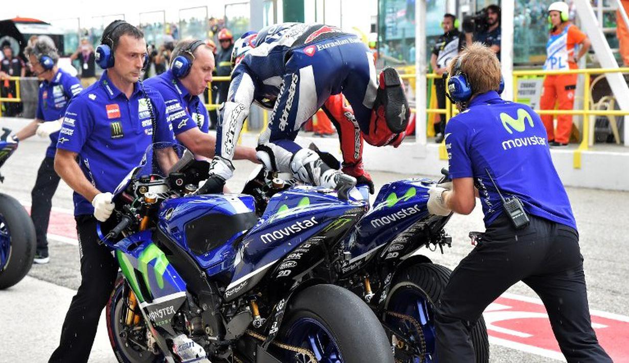 Pebalap Yamaha, Jorge Lorenzo, melompat ke motor pengganti setelah hujan turun saat balapan MotoGP San Marino di Sirkuit Misano, Minggu (13/9/2015). (AFP Photo/Vincenzo Pinto)