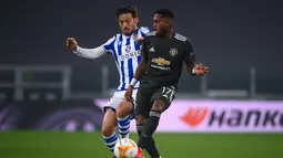 Gelandang Real Sociedad, Mikel Merino berusaha merebut bola dari gelandang Manchester United, Fred pada pertandingan leg pertama babak 32 besar Liga Europa di stadion Juventus, Turin (19/2/2021). MU menang telak atas Sociedad 4-0.  (AFP/Marco Bertorello)