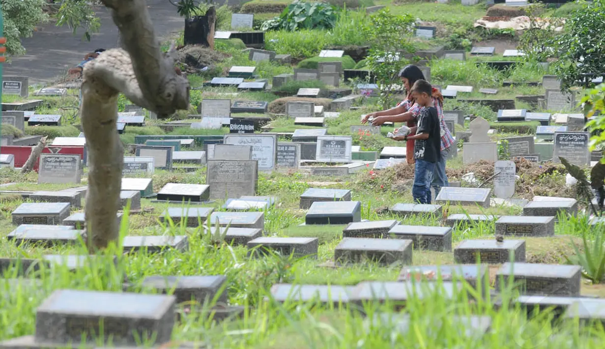 Sebuah keluarga tampak melakukan tabur bunga di salah satu makam yang ada di TPU Karet Bivak, Jakarta, Senin (23/6/14). (Liputan6.com/Herman Zakharia)