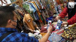Pengunjung melakukan transaksi menggunakan QR Code BCA mobile pada pameran Adi Wastra Nusantara di Jakarta (11/2/2022). Ketiga pilar utama diimplementasikan pada pameran Adi Wastra Nusantara 2022 yang menghadirkan kain tradisional dari seluruh daerah di Indonesia. (Liputan6.com/HO/Eko)