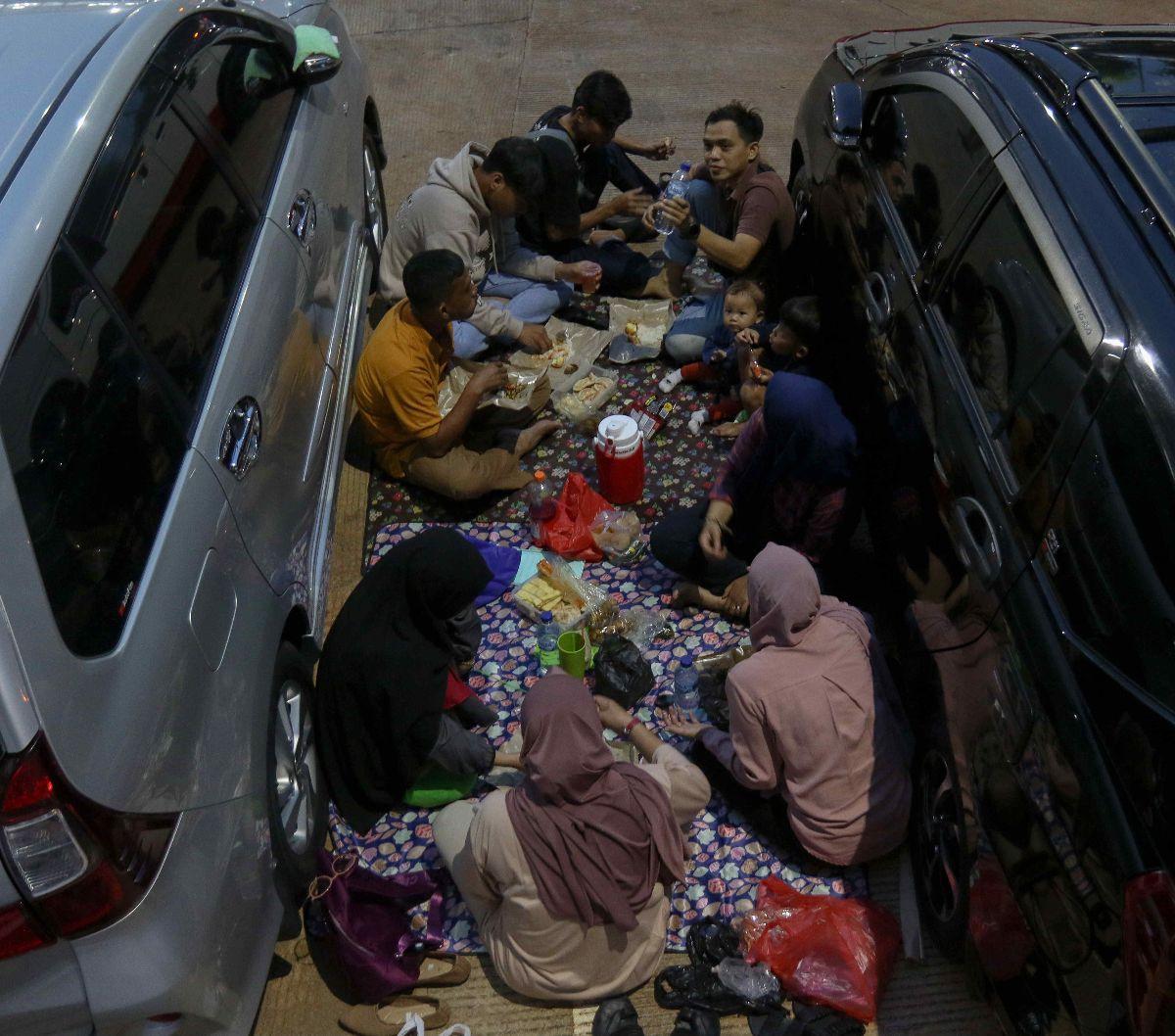 Pemudik menggelar tikar dan menyantap hidangan berbuka puasa di antara mobil yang terparkir di rest area Tol Cipalo KM 102, Subang, Jawa Barat, Sabtu (6/4/2024).&nbsp;Pada puncak arus mudik Lebaran, rest area di sepanjang Tol Trans Jawa menjadi tempat fav