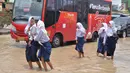 Sejumlah pelajar melintasi genangan banjir di kawasan Sawah besar Semarang, Jawa Tengah, Sabtu (8/12). Tingginya curah hujan dan banyaknya tumpukan sampah diduga menjadi penyebab jebolnya tanggul. (Liputan6.com/Gholib)