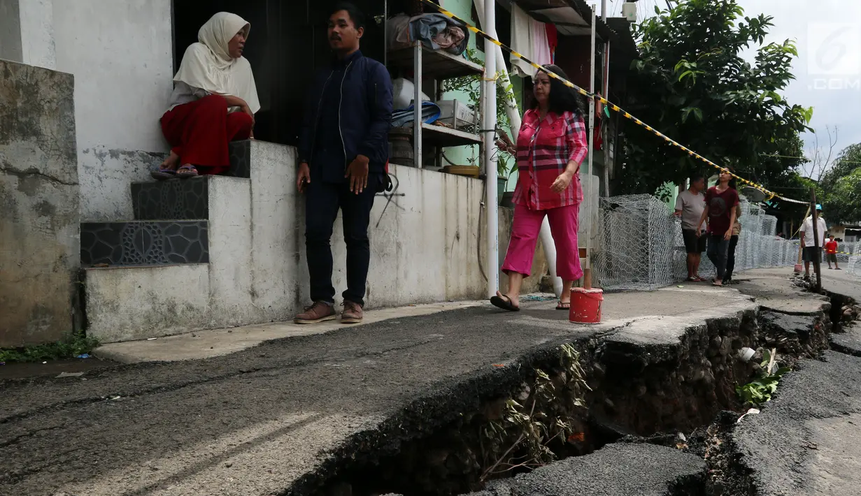 Warga beraktivitas di dekat jalan yang retak di Kelurahan Kebon Manggis, Kecamatan Matraman, Jakarta Timur, Jumat (16/2). Kendaraan yang ingin melintasi jalan tersebut dialihkan ke jalan-jalan lain di sekitarnya. (Liputan6.com/Johan Tallo)