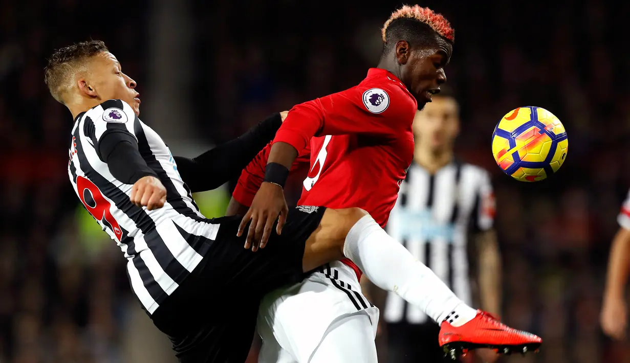 Pemain Newcastle United, Dwight Gayle berb=ebut boola dengan pemain Manchester United, Paul Pogba pada laga lanjutan Premier League pekan ke-12 di Old Trafford, Minggu (19/11). MU menang telak 4-1 atas Newcastle. (Martin Rickett/PA via AP)