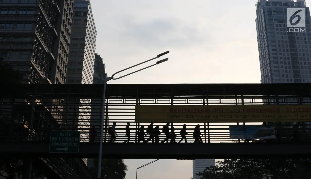 Pejalan kaki melintas di JPO Jalan Sudirman yang dipasangkan Spanduk peringatan revitalisasi, Jakarta (6/11). Ketiga JPO yang akan direvitalisasi mendapatkan penambahan lift dan CCTV. (Liputan6.com/Immanuel Antonius)