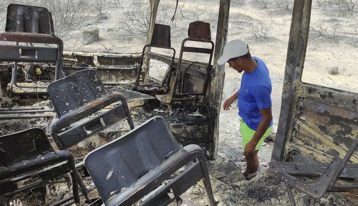 Seorang pria melihat sebuah van yang hangus terbakar di sebuah desa di wilayah El Tarf, dekat perbatasan utara Aljazair-Tunisia, Kamis (18/8/2022). Kebakaran yang melanda di hutan Aljazair timur telah menewaskan sedikitnya 26 orang, menurut untuk "laporan sementara" oleh menteri dalam negeri negara Afrika utara itu. (AP Photo/Mohamed Ali)