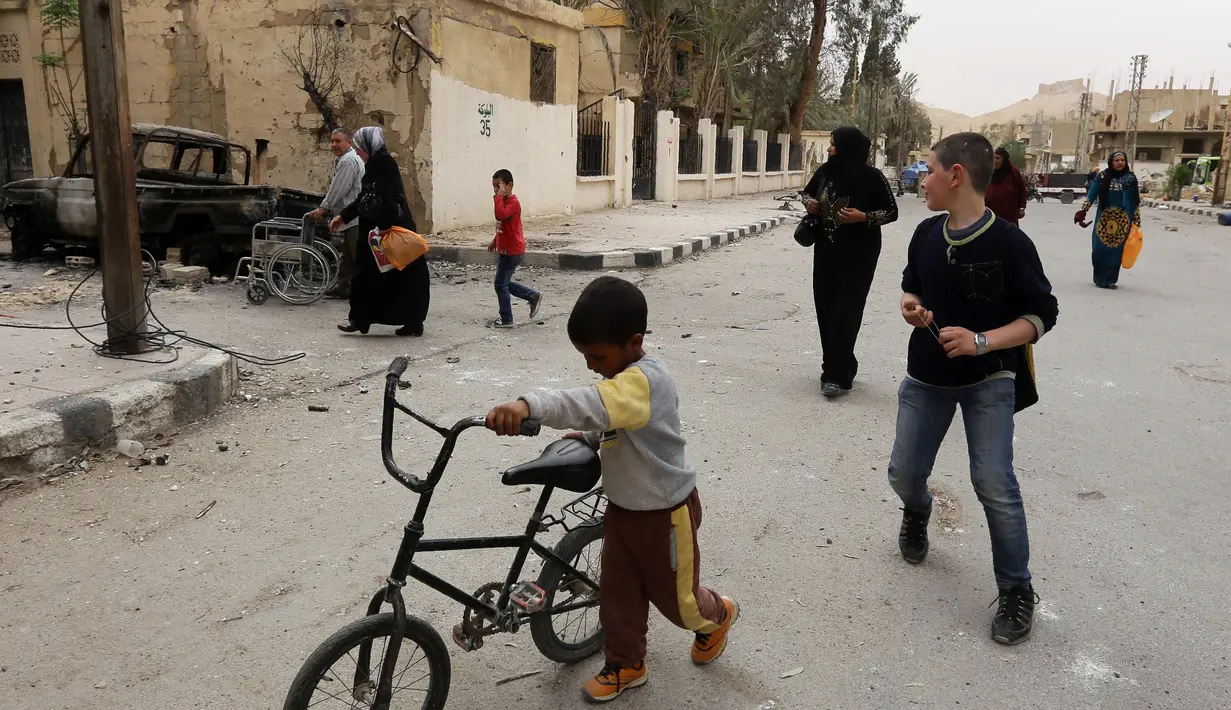 Sejumlah orang mulai kembali ke rumah mereka di kota modern Palmyra, berdekatan dengan kota kuno Suriah, Sabtu (9/4). Kota itu berhasil direbut kembali oleh militer Suriah dari tangan kelompok ekstrimis ISIS beberapa waktu lalu. (Louai BESHARA/AFP)