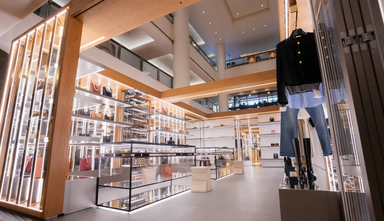 Etalase kaca ramping berbingkai logam hitam matte dan lampu LED yang menggantung menciptakan suasana minimalis namun tetap memukau. Aksen baja dan kayu alami menambah kehangatan dan tekstur, memberikan sentuhan organik halus yang melengkapi kode desain CELINE yang tak lekang oleh waktu. [Celine]