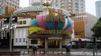 Pejalan kaki melewati Kasino Lisboa yang telah ditutup menyusul ancaman Topan Mangkhut di Makau, Minggu (16/9). Makau menutup semua kasino untuk pertama kalinya dalam sejarah akibat badai terbesar tahun ini mendekati Makau. (AFP/ISAAC LAWRENCE)