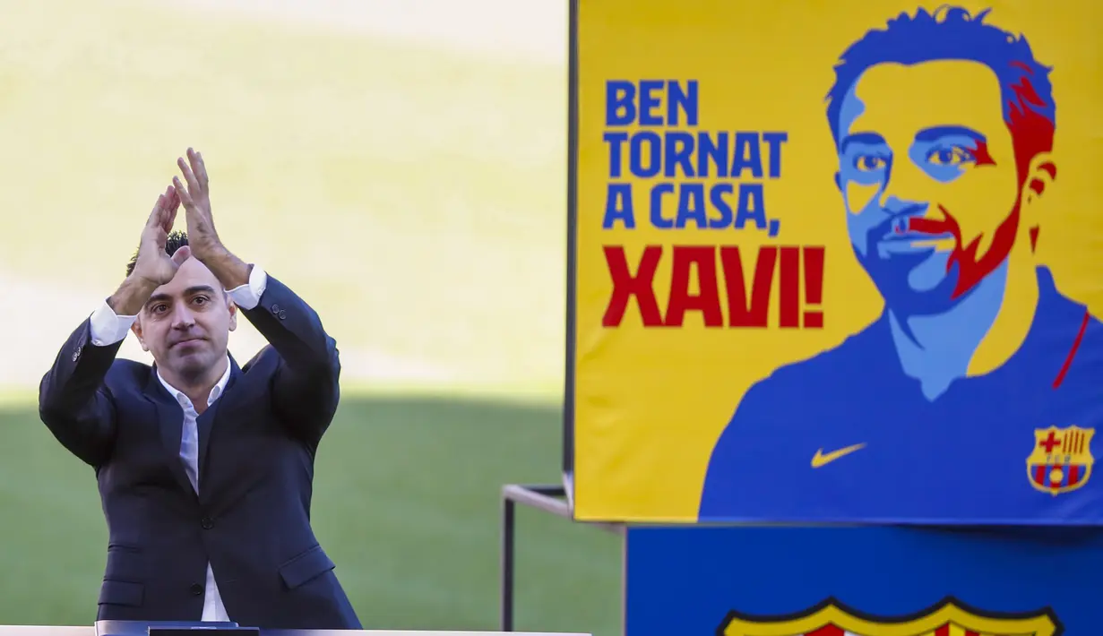 Pelatih baru Barcelona Xavi Hernandez melambai ke penonton saat presentasi resminya di stadion Camp Nou, Spanyol, Senin (8/11/2021). Xavi, yang berkembang di lini tengah Barcelona bersama Messi dan Andres Iniesta, secara resmi diperkenalkan sebagai pelatih Barcelona. (AP Photo/Joan Monfort)