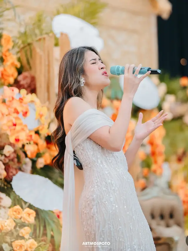 Raisa saat nyanyi di kondangan pakai dress putih senada dengan antingnya. [@artmospoto]