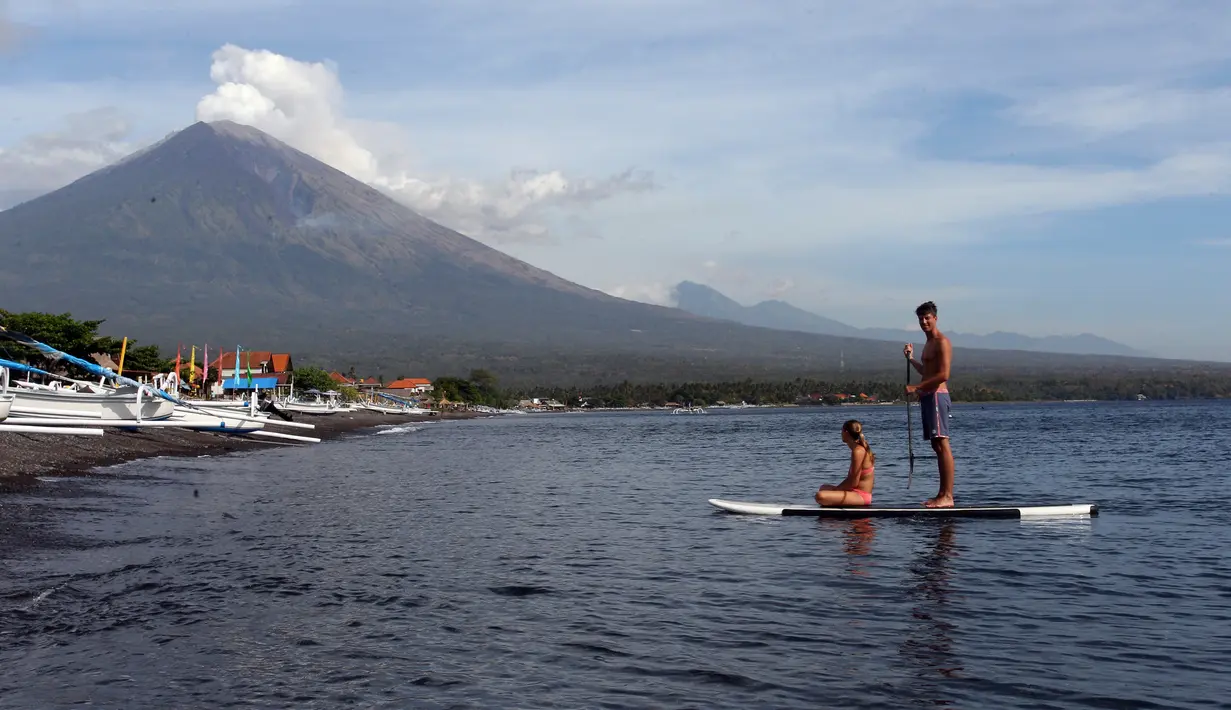 Wisatawan mengayuh kano sambil menyaksikan Gunung Agung yang kembali meletus terlihat dari Karangasem, Bali, Selasa (3/7). Pagi ini, Gunung Agung kembali meletus disertai abu vulkanik setinggi 2.000 meter di atas puncak. (AP Photo/Firdia Lisnawati)