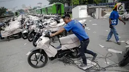 Pekerja menyiapkan motor yang akan dikirim menggunakan kereta di Stasiun Pasar Senen, Jakarta, Jumat (23/6). (Liputan6.com/Faizal Fanani)