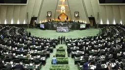 Anggota parlemen Iran mengangkat tangan saat voting RUU yang menetapkan pasukan militer Amerika Serikat sebagai teroris, Teheran, Selasa (7/1/2020). Dalam RUU itu seluruh pasukan militer AS serta pihak terkait pembunuhan Jenderal Qasem Soleimani ditetapkan sebagai teroris. (ICANA NEWS AGENCY/AFP)