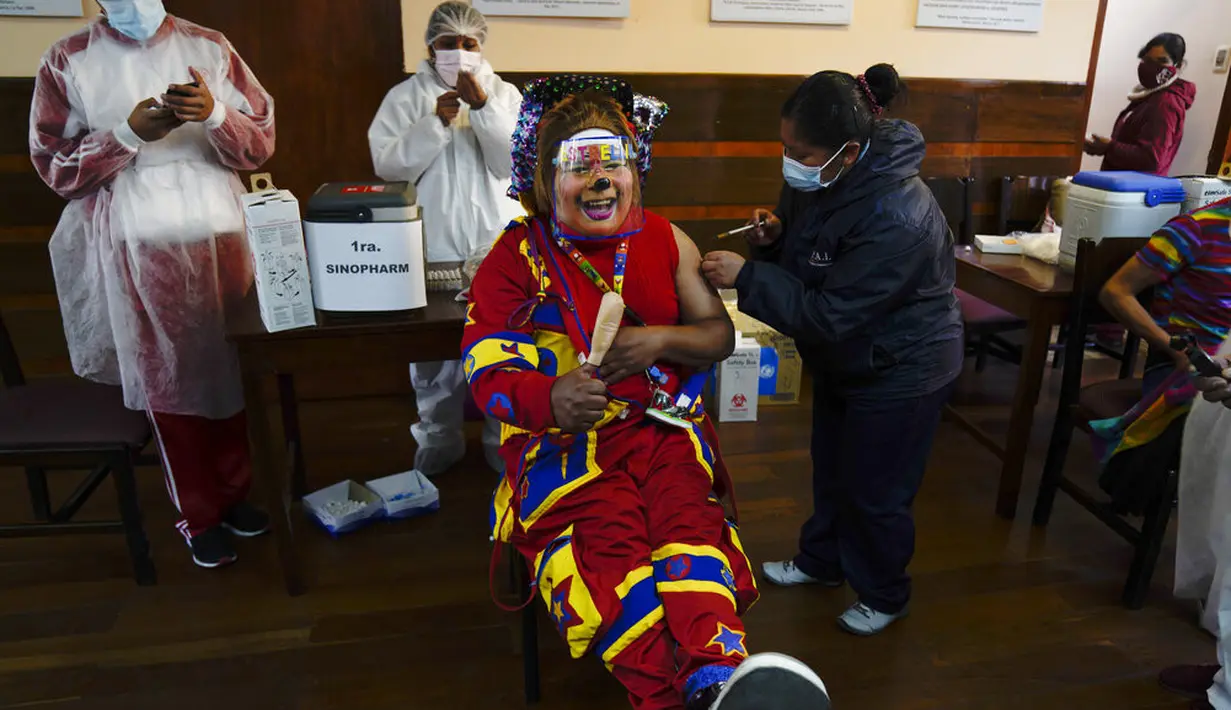 Seorang badut disuntik vaksin COVID-19 Sinopharm selama kampanye vaksinasi yang menargetkan usia antara 18 dan 30 tahun di Universitas Negeri San Andres di La Paz, Bolivia, Senin (5/7/2021). Presiden Luis Arce menjanjikan upaya vaksinasi "besar-besaran" pada Juli dan Agustus. (AP Photo/Juan Karita)