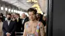 Musisi Harry Styles berjalan di red carpet saat tiba untuk ajang Grammy Awards 2023 di Crypto.com Arena, Los Angeles, AS, Minggu Malam (6/2/2023) waktu setempat. Kehadiran Harry Styles menarik perhatian fotografer saat dia melenggang tanpa mengenakan baju atasan. (Neilson Barnard / Getty Images via AFP)