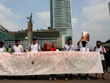 Sekelompok warga membentangkan Petisi Penolakan Kenaikan Tarif Dasar Listrik di kawasan Bundaran HI, Jakarta, Minggu (7/5). Mereka meminta pihak berwenang mengkaji kembali kebijakan kenaikan tarif dasar listrik. (Liputan6.com/Helmi Fithriansyah)