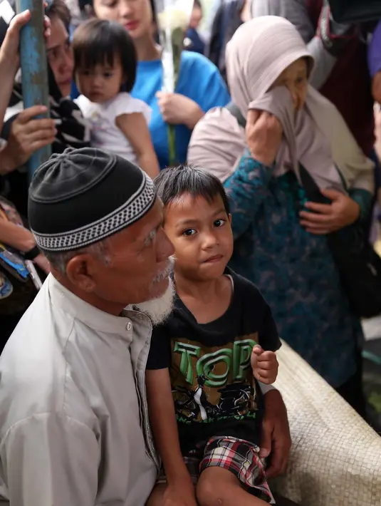 Anak semata wayangnya Iren, Al Mufthi bersama kakeknya saat mengikuti proses pemakanan. Suasana semakin haru ketika bocah lima tahun itu, ikut dimasukkan dalam liang lahat. (Nurwahyunan/Bintang.com)