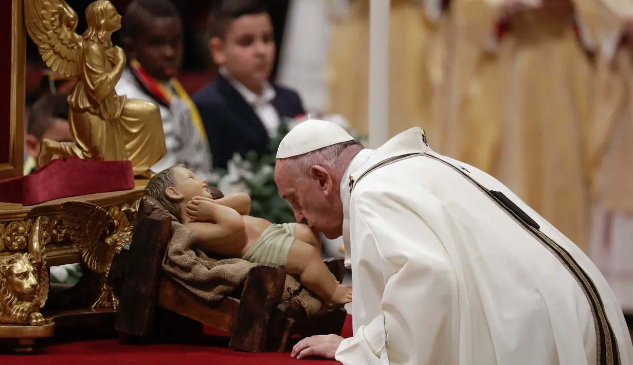 Paus Fransiskus mencium patung bayi Yesus ketika memimpin misa Malam Natal di Basilika Santo Petrus, Vatikan, Selasa (24/12/2019). Paus Fransiskus memimpin Natal bagi 1,3 miliar umat Katolik dunia. (AP Photo/Alessandra Tarantino)