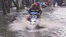 Pengendara motor menerjang banjir di Jalan KH. Ahmad Dahlan Cipondoh, Tangerang, Selasa (16/2/2021). Hujan deras yang melanda wilayah Tangerang mengakibatkan ruas jalan alternatif penghubung Tangerang dengan Jakarta tersebut banjir setinggi lutut orang dewasa. (Liputan6.com/Angga Yuniar)