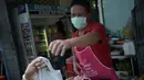 Seorang pria memakai masker memberikan makanan ke pelanggannya di Bangkok, Thailand, (19/6/ 2015). Pemerintah Thailand mengumumkan bahwa seorang pria 75 tahun asal Oman positif terjangkit virus MERS.  (AFP PHOTO/Christophe Archambault)