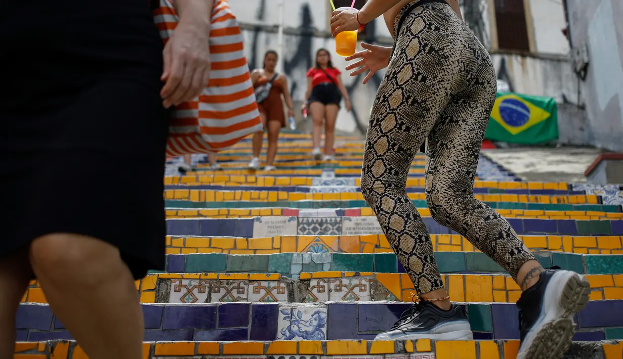 Orang-orang berlalu-lalang di anak tangga yang terkenal dengan nama Selaron Steps atau Escadaria Selarón di Rio de Janeiro, Brasil pada 9 Desember 2019. Escadaria Selaron merupakan 250 anak tangga sepanjang 125 meter dengan dua ribuan ubin berwarna-warni. (Photo by David GANNON / AFP)