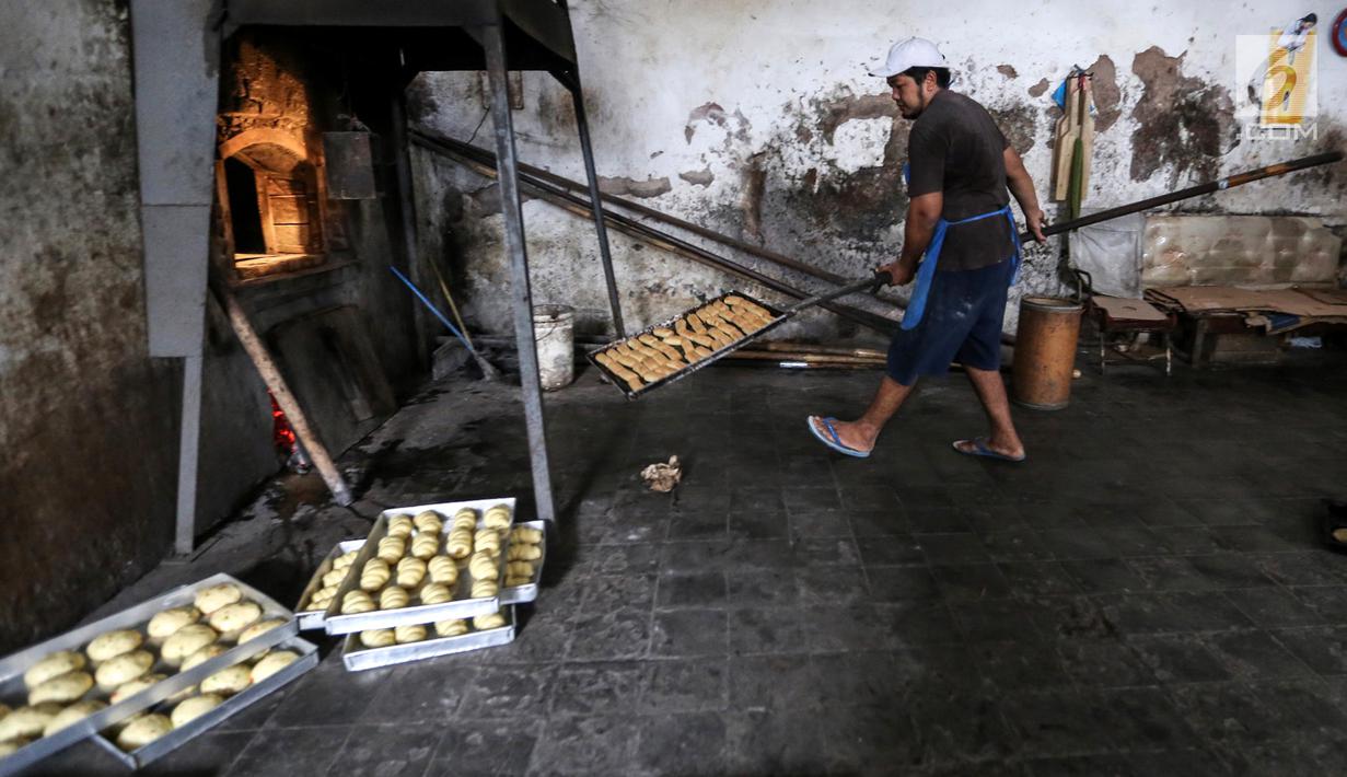 Karyawan mengeluarkan roti usai dipanggang dari dalam tungku di Toko Roti GO, Purwokerto, Jawa Tengah, Senin (22/4). Toko roti yang berdiri sejak tahun 1898 tersebut diproduksi dengan fermentasi (bibit roti) dan tanpa bahan campuran atau pengawet. (Liputan6.com/Fery Pradolo)