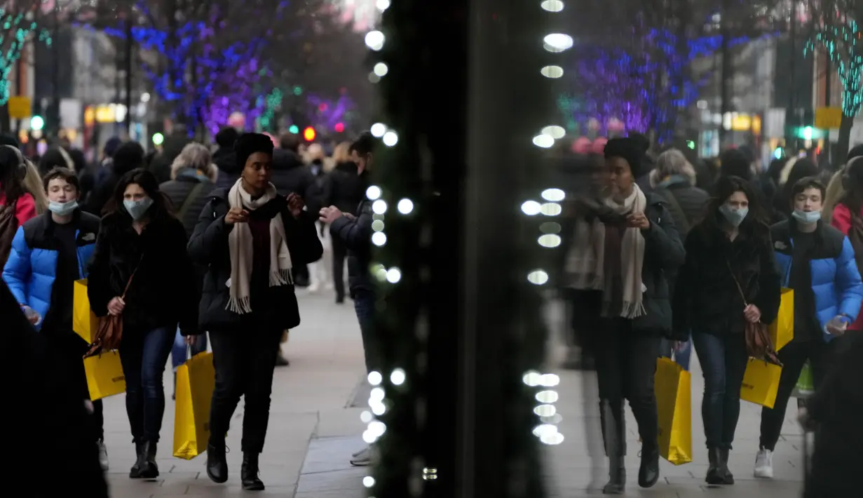 Pembeli terpantul di jendela saat mereka berjalan di Oxford Street, jalan perbelanjaan tersibuk di Eropa, di London, Kamis (23/12/2021). Meskipun pandemi covid-19, salah satu pusat perbelanjaan di London tersebut begitu ramai menjelang Natal. (AP Photo/Frank Augstein)