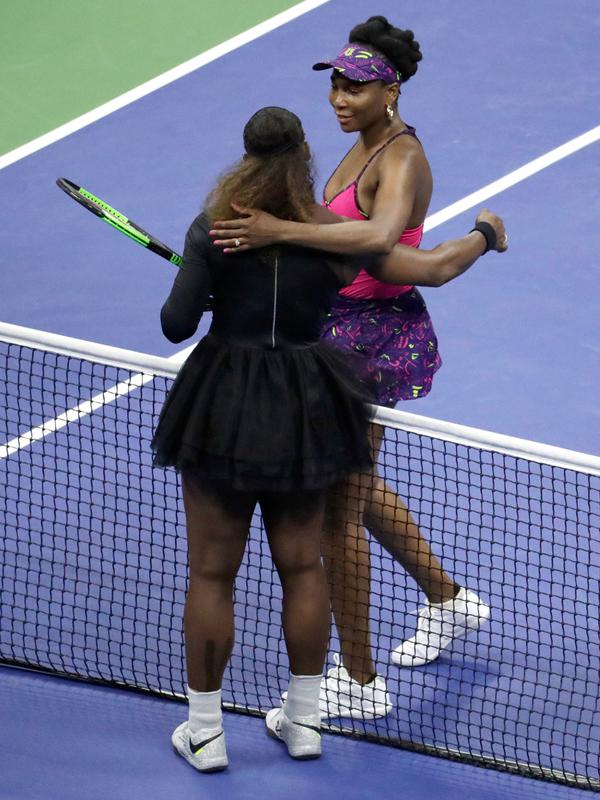 Petenis Serena Williams (kiri) memeluk kakak perempuannya, Venus Williams usai bertanding di putaran ketiga turnamen tenis AS Terbuka di New York, Jumat (31/8). Serena mengalahkan Venus dengan skor 6-1, 6-2. (AP Photo/Julio Cortez)