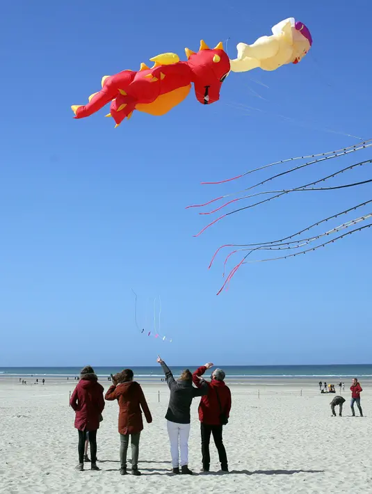 Pengunjung menyaksikan layang-layang terbang selama Festival Layang-layang Internasional ke-31 di Berck, Prancis, (6/4). Festival ini diselenggarakan di Berck-sur-Mer setiap bulan April dan berlangsung selama 10 hari. (AP Photo / Thibault Camus)