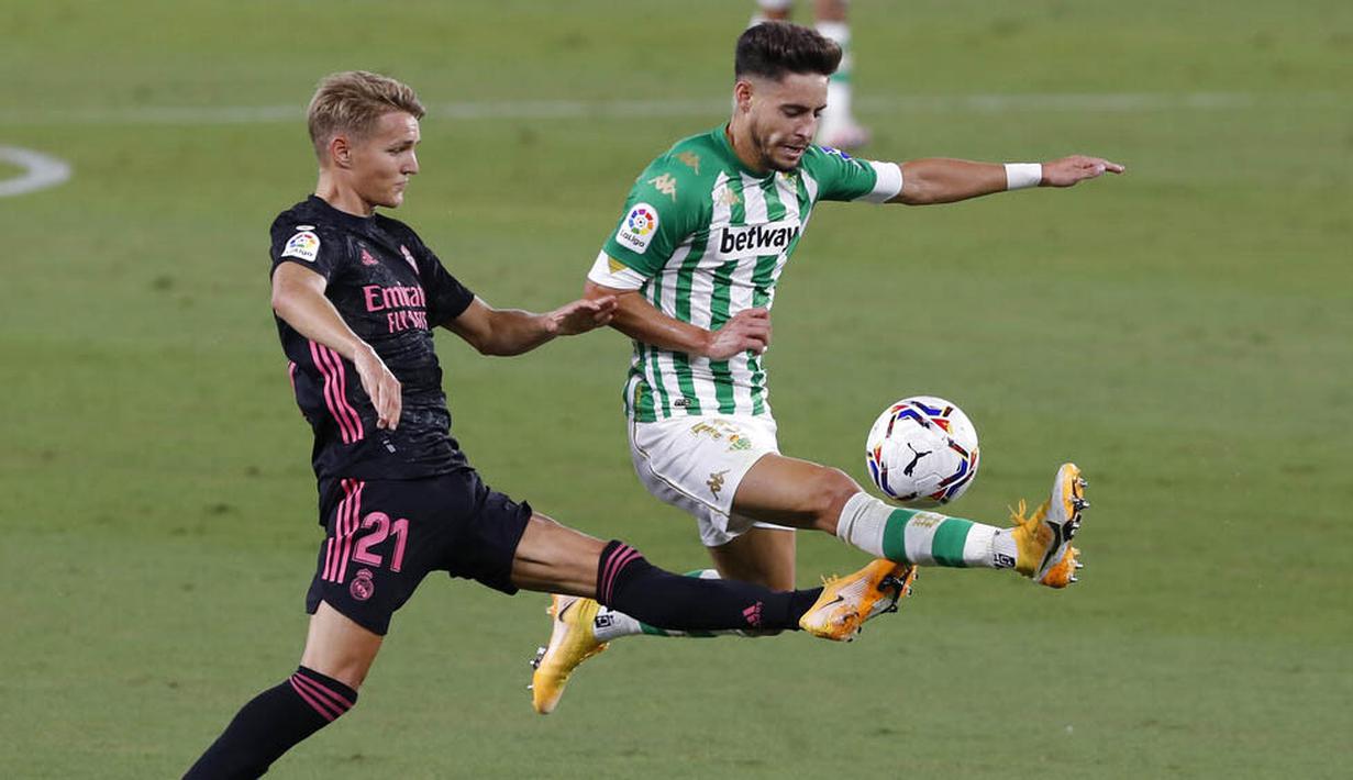 Pemain Real Madrid, Martin Odegaard, berebut bola dengan pemain Real Betis, Alex Moreno, pada laga La Liga di Stadion Benito Villamarin, Minggu (27/9/2020). Real Madrid menang dengan skor 3-2. (AP Photo/Angel Fernandez)