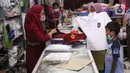 Pedagang melayani pembeli seragam sekolah baru di salah satu toko di Tangerang, Banten, Selasa (2/6/2020). Menjelang tahun ajaran baru, sejumlah pedagang di tempat tersebut mengeluh karena omzet penjualan seragam sekolah menurun drastis akibat pandemi COVID-19. (Liputan6.com/Angga Yuniar)