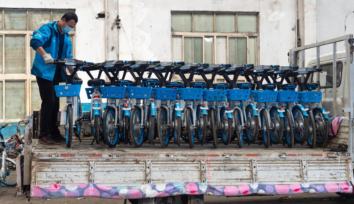 Seorang staf memindahkan sepeda listrik untuk layanan berbagi kendaraan dari truk ke area parkir di Distrik Fancheng di Kota Xiangyang, Provinsi Hubei, China tengah (24/4/2020). (Xinhua/Xie Jianfei)