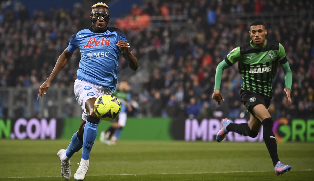 Pemain Napoli, Victor Osimhen (kiri) mengontrol bola dibayangi pemain Sassuolo dalam pertandingan pekan ke-23 Liga Italia 2022/2023 yang berlangsung di Mapei Stadium, Sabtu (18/2/2023). Victor Osimhen kini telah mencetak 18 gol dan menjadi top skor sementara Liga Italia musim ini. (AP/LaPresse/Massimo Paolone)