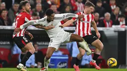 Pemain Real Madrid, Jude Bellingham, berebut bola dengan pemain Athletic Bilbao, Mikel Jauregizar (kanan) dan Yeray Alvarez (kiri), pada laga lanjutan Liga Spanyol 2024/2025 di San Mames Stadium, Bilbao, Spanyol, Kamis (05/12/2024) dini hari WIB. (AP Photo/Miguel Oses)