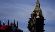 Seorang perempuan mengenakan masker saat melintasi Jembatan Westminster di London, Kamis (9/12/2021). Perdana Menteri Inggris Boris Johnson telah mengumumkan pembatasan yang lebih ketat untuk membendung penyebaran varian baru Covid-19, omicron. (AP Photo/Frank Augstein)