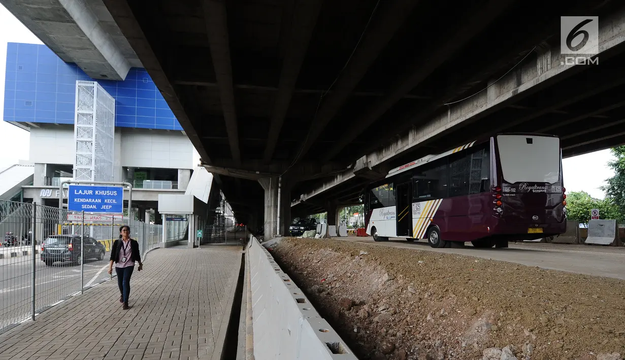 Pejalan kaki melintas dekat bus premium Transjakarta atau Royaltrans yang sedang menunggu penumpang di pul Royaltrans di kolong Tol Simatupang, Jakarta, Selasa (23/4). Dua rute bus Royaltrans berangkat dari pul ini, yakni S12 (BSD-Fatmawati) dan S31 (Blok M-Bintaro). (Liputan6.com/Herman Zakharia)