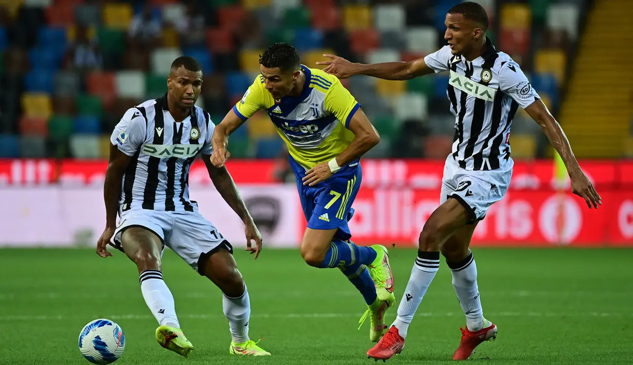 Pemain Juventus Cristiano Ronaldo (tengah) dilanggar pemain Udinese Rodrigo Becao pada pertandingan Liga Italia Serie A di Dacia Arena Stadium, Udine, Italia, 22 Agustus 2021. Pertandingan berakhir dengan skor 2-2. (MIGUEL MEDINA/AFP)