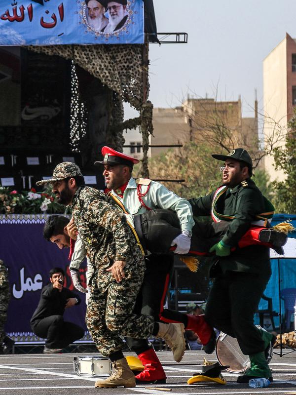Tentara membawa pergi rekan mereka yang terluka saat terjadi serangan pada parade militer di Kota Ahvaz, Iran, Sabtu (22/9). Parade militer ini untuk memperingati pecahnya perang Iran-Irak pada 1980-1988. (MORTEZA JABERIAN/ISNA/AFP)
