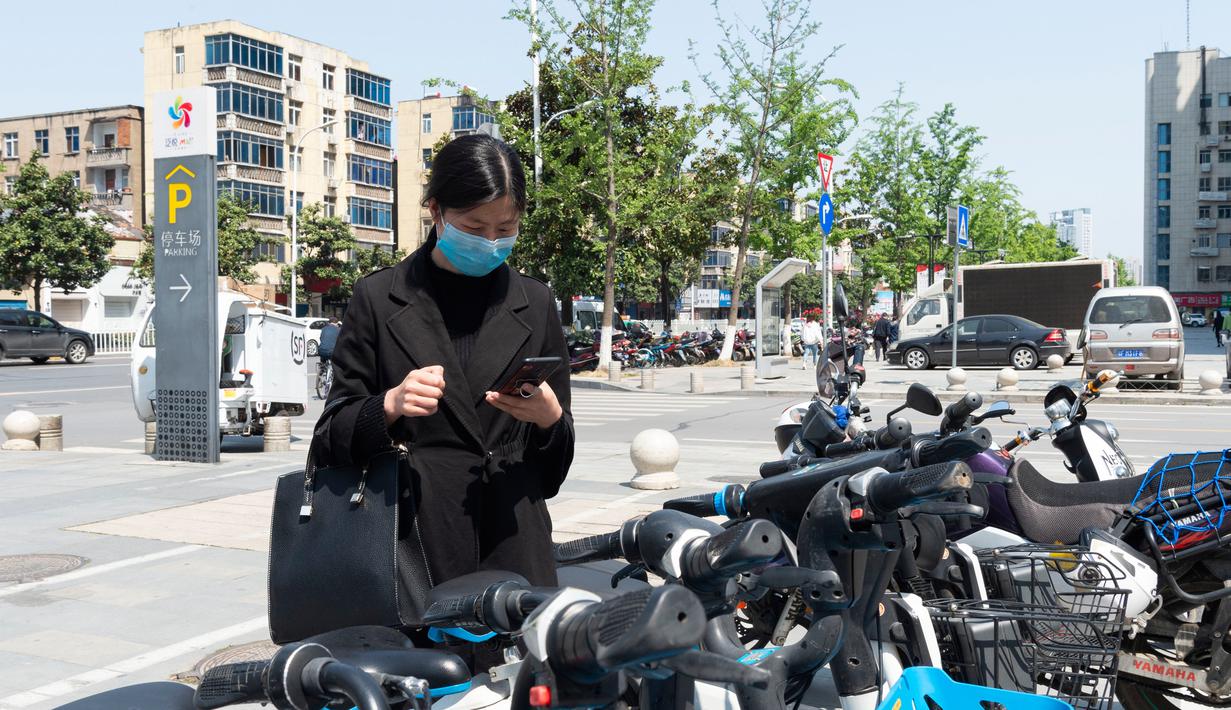 Seorang warga memindai kode respons cepat (QR) pada layanan berbagi sepeda listrik dengan ponsel pintar di Distrik Fancheng di Kota Xiangyang, Provinsi Hubei, China tengah (24/4/2020). (Xinhua/Xie Jianfei)
