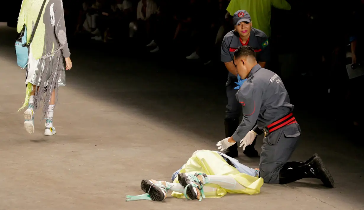 Petugas medis berusaha menyelamatkan model Tales Cotta saat terjatuh di catwalk Sao Paulo Fashion Week, Sao Paulo, Brasil, 27 April 2019. Model asal Brasil tersebut mendadak jatuh sakit dan meninggal saat mengikuti peragaan busana. (REUTERS/Leco Viana)
