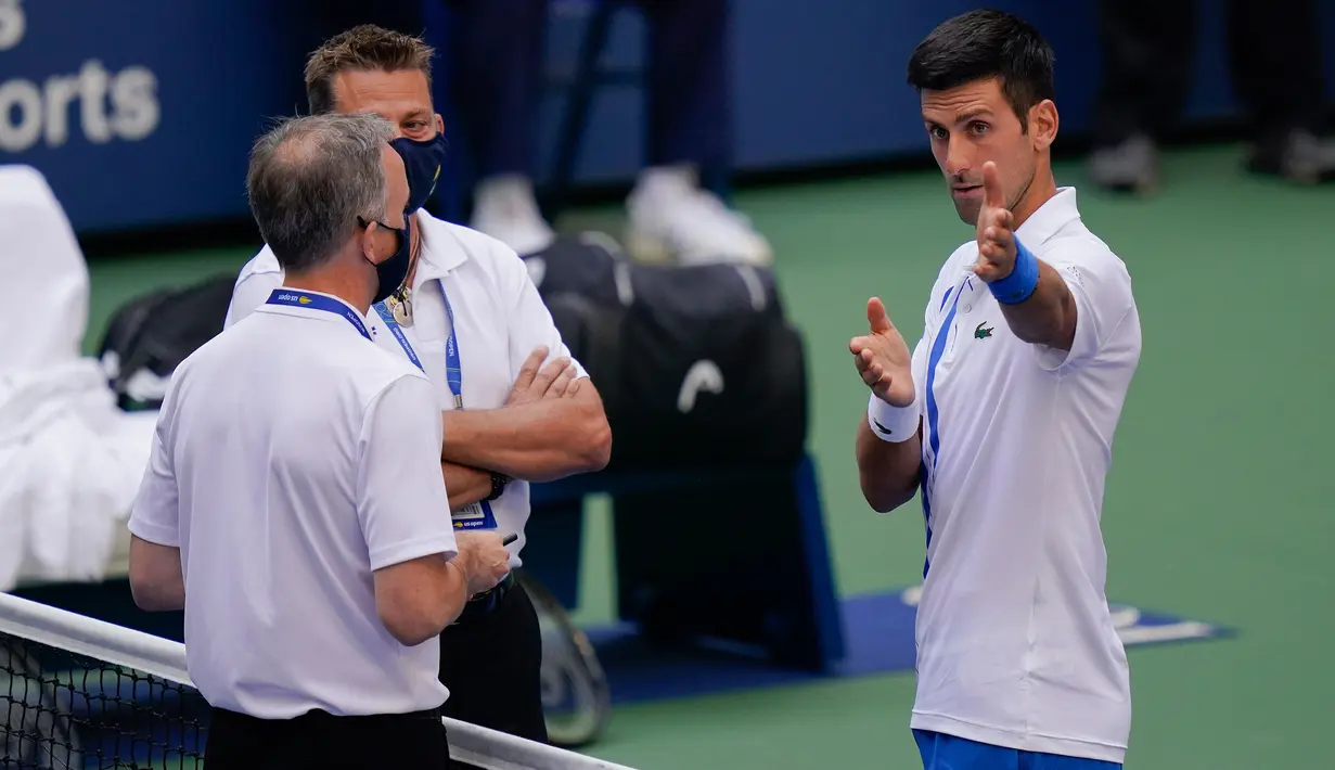 Petenis Serbia, Novak Djokovic berbicara dengan wasit setelah hantaman bolanya mengenai hakim garis saat kehilangan poin dari Pablo Carreno Busta (Spanyol) pada putaran keempat US Open 2020, di Flushing Meadows, (6/9/2020). Djokovic pun didiskualifikasi dari AS Terbuka 2020. (AP Photo/Seth Wenig)