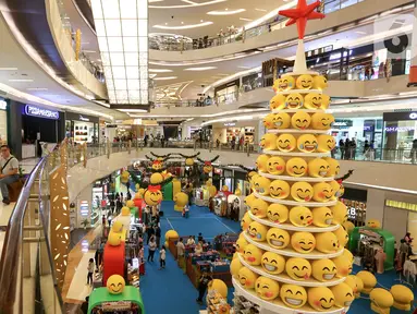 Pengunjung melintas di samping pohon Natal yang didominasi warna kuning setinggi 12 meter di Lippo Mall Kemang,  Jakarta Sabtu (14/12/2019). Pohon dengan konsep Joypixels Emoji momentum liburan menyambut Natal bersama keluarga. (Liputan6.com/Fery Pradolo)