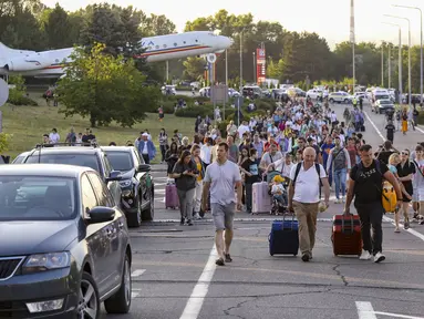 Wisatawan berjalan ke Bandara Chisinau saat kembali dibuka setelah penutupan yang dipicu oleh penembakan dalam terminal, Chisinau, Moldova, Jumat (30/6/2023). Penembakan tersebut menewaskan dua orang. (AP Photo/Aurel Obreja)