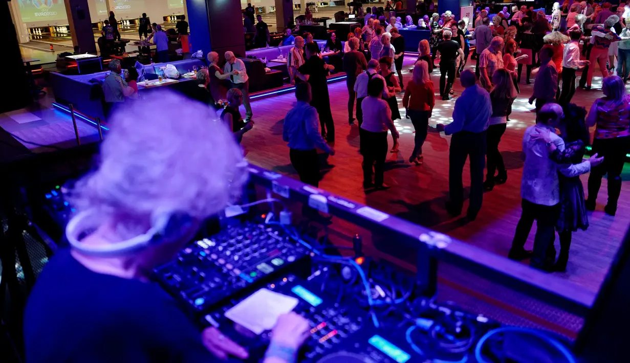 Pengunjung berjoged saat DJ Wika Szmyt memainkan musik di sebuah klub di Warsawa, Polandia, Senin (25/3). Di usianya yang menginjak 80 tahun, Wika masih aktif menghibur di salah satu klub di Warsawa. (REUTERS/Kacper Pempel)