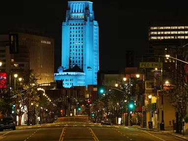 Balai Kota Los Angeles menyala biru saat Broadway terlihat sepi, Los Angeles, Amerika Serikat, Jumat (10/4/2020). Balai Kota dan beberapa landmark Los Angeles menyala biru untuk menunjukkan dukungan kepada petugas medis mengahadapi virus corona COVID-19. (AP Photo/Mark J. Terrill)