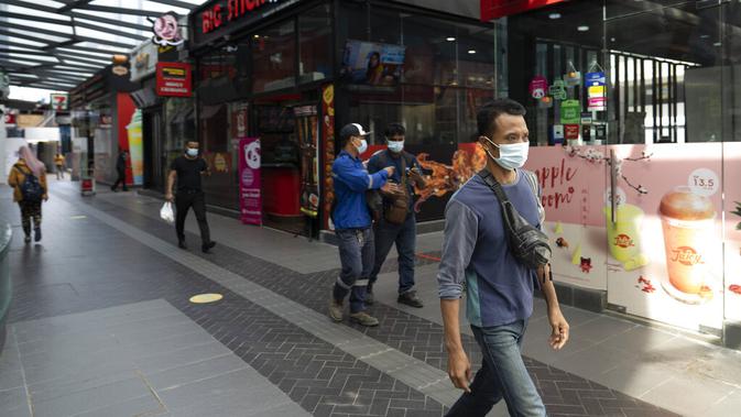 Para pejalan kaki memakai masker saat berjalan di distrik perbelanjaan di Kuala Lumpur, Malaysia, Kamis (14/1/2021). Otoritas Malaysia memperketat pembatasan pergerakan untuk mencoba menghentikan penyebaran virus corona COVID-19. (AP Photo/Vincent Thian)
