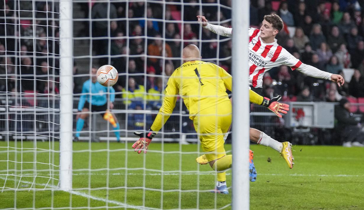 <p>Kiper Sevilla, Marko Dmitrovic berusaha menghalau bola dari ancaman pemain PSV, Guus Til dalam laga leg kedua babak playoff fase gugur Liga Europa 2022/2023 di Philips Stadium, Eindhoven, Jumat (24/2/2023). (AP Photo/Peter Dejong)</p>