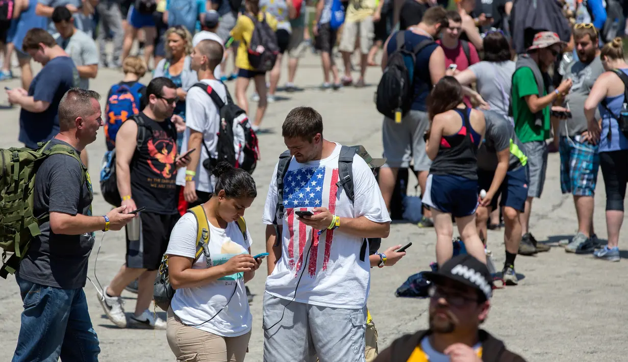 Para peserta berpencar mencari pokemon di Giant Park, Chicago, Sabtu (22/7). Baru dimulai, terjadi masalah dengan jaringan selular dan server dalam permainan Pokemon Go sehingga menghambat peserta dalam mengikuti acara tersebut. (AP/Erin Hooley)