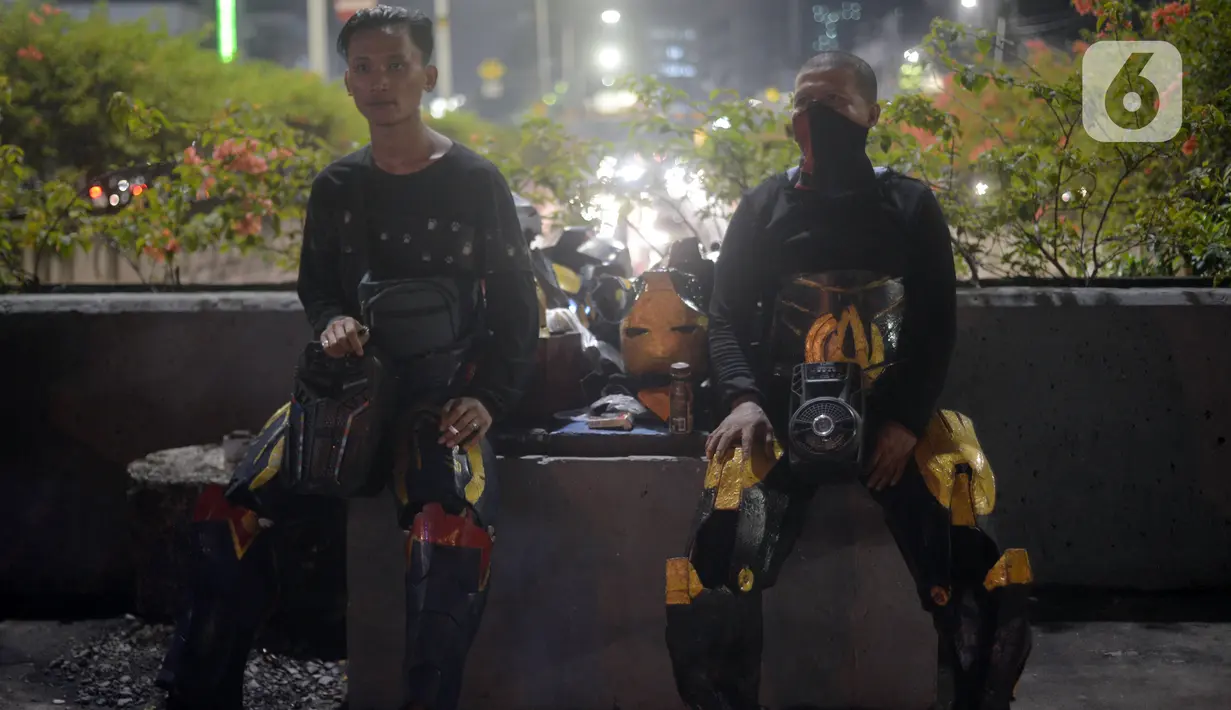 Abi (20) dan Nujum (48) mengenakan kostum robot di kawasan Tomang, Jakarta, Selasa (14/9/2021). Abi dan Nujum mengenakan kostum robot Iron Man untuk mengais rejeki dan menghibur para pengendara dari kemacetan lalu lintas yang dilakukan sejak pandemi COVID-19. (merdeka.com/Imam Buhori)